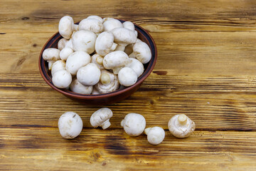 Sticker - Fresh champignon mushrooms in ceramic bowl on the wooden table