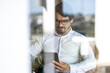 © Joao - Businessman wearing glasses sitting looking to his tablet. Successful male portrait with positive attitude working from home
