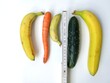 Tape measure and two bananas, one cucumber and one carrot against white background