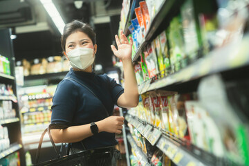 new normal after covid epidemic young smart asian female shopping new lifestyle in supermarket with face shild or mask protection hand choose consumer products new normal lifestyle