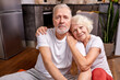 senior couple having rest on the floor after yoga exercises, in sportive wear, look at camera and smile