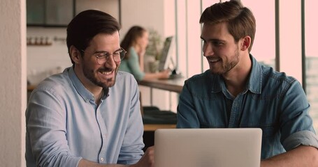 Wall Mural - Happy 35s young employee in eyeglasses sharing working results on computer with skilled millennial colleagues, discussing ideas, solving problems together or analyzing research results data in office.