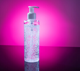 Cosmetic product for makeup remover. Clear liquid with small air bubbles on purple backgroud. Bottle with dispenser.