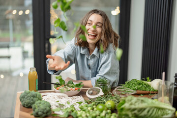 Wall Mural - Young pretty woman enjoying and cooking healthy diet salad in the kitchen. Wellness and health care concept. High quality photo