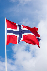 Norwegian flag in wind on blue  and white sky background