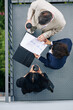 © DragonImages - Business colleagues standing on fire escape staircase, drinking take out coffee and analyzing sales reports