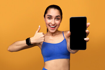 Happy sporty lady showing phone with blank empty screen