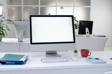 Desktop computer with illuminated screen and cup at workstation in abandoned office