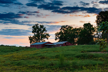 Landscape old red barns against vivid sunrise