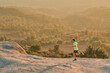© Albert Garrido/ADDICTIVE STOCK - Side view of slim male runner running on rocks in mountains at sunset in evening during active training