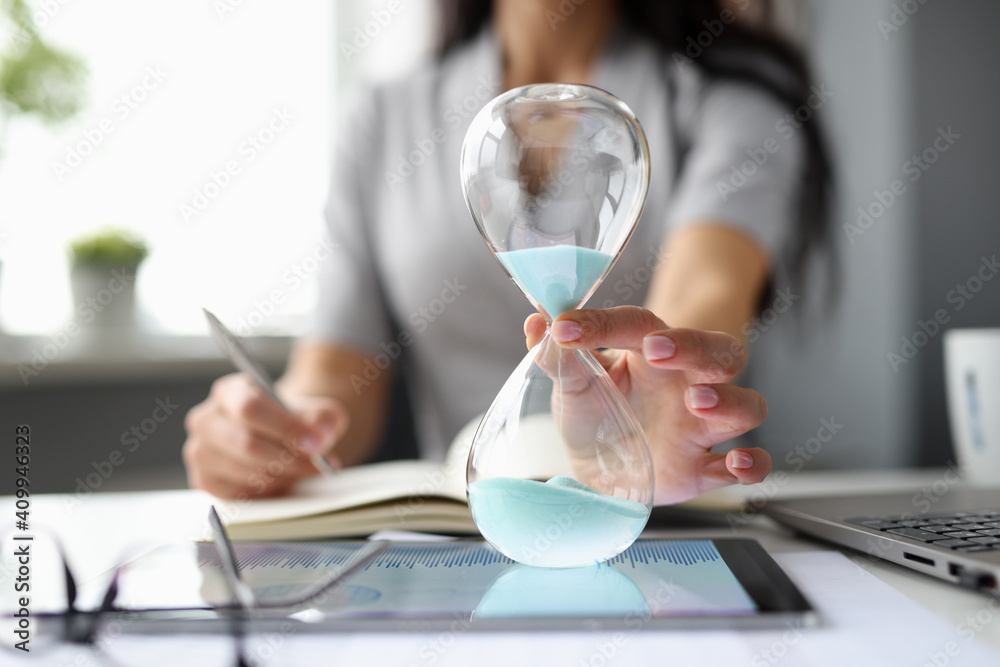Business woman putting hourglass on digital tablet closeup - obrazy, fototapety, plakaty 