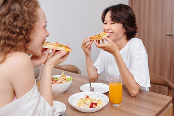 Canvas Print - Cheerful hungry young women having delicious pizza, salad and apple slices for dinner