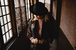 © Carlos Pintau/ADDICTIVE STOCK - Stylish female in elegant vintage outfit and hat standing in narrow hallway of old house and looking at mirror