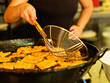 © Cien X Cien Studio/ADDICTIVE STOCK - Crop unrecognizable chef with metal ladle frying pieces of dough in pan with hot oil while working in professional kitchen