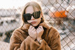 © Carlos Rodelas/ADDICTIVE STOCK - Young determined female in sunglasses and warm jacket standing near net fence and looking at camera