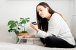 © Chris Leon/ADDICTIVE STOCK - Female buyer sitting on sofa at home and making payment with plastic card while shopping online via laptop