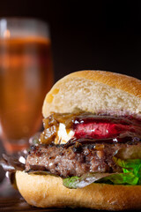 Poster - Vertical shot of a tasty-looking burger near a beer glass on a dark background