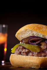 Canvas Print - Vertical shot of a tasty-looking burger near a beer glass on a dark background