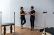© David Fuentes/ADDICTIVE STOCK - Cheerful sportsman and sportswoman standing in bright gym and talking to each other while relaxing during pilates training
