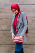 © David Munoz/ADDICTIVE STOCK - Side view of young content Arab female in hijab and trendy clothes standing near building in city and looking down