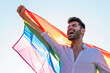 © David Munoz/ADDICTIVE STOCK - Low angle of expressive homosexual male standing on street with bright rainbow flag and cheerfully screaming