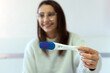 © David Munoz/ADDICTIVE STOCK - Young blurred female smiling and showing modern plastic pregnancy test with negative result at camera