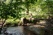 © Galdric Penarroja/ADDICTIVE STOCK - Calm female sitting on old bridge over river in woods and enjoying nature in summer
