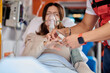 © Gabriel Trujillo/ADDICTIVE STOCK - Crop male paramedic putting finger pulse oximeter on patient in ventilator mask lying on medical stretcher in ambulance car