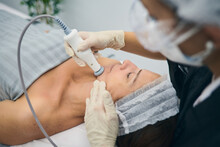 Professional Dermatologist Applying RF Lifting Machine On Face Of Mature Woman During Skin Care Treatment In Beauty Clinic
