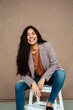 © Jake Jakab/ADDICTIVE STOCK - Stylish cheerful ethnic female model in trendy smart casual outfit sitting on chair and looking confidently at camera