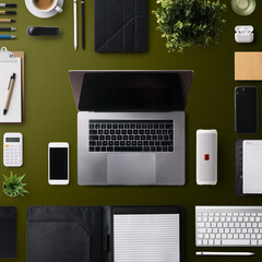 Flat lay top view office desk working space with laptop and office supplies on dark background.