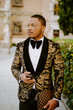 © Jake Jakab/ADDICTIVE STOCK - Side view of rich African American male in posh tuxedo standing in street while browsing on smartphone looking away