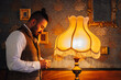 © Javier De La Torre/ADDICTIVE STOCK - Side view of serious bearded man with chain in hand standing near old fashioned lamp in classic room