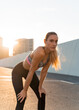 © Jordi Bataller/ADDICTIVE STOCK - Young fit female athlete in sportswear bending on asphalt road after exercising in sunlight in back lit and looking at camera