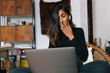 © Joy Zamora/ADDICTIVE STOCK - Low angle of astonished Indian female sitting with laptop and reading news online while covering mouth