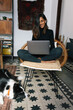 © Joy Zamora/ADDICTIVE STOCK - Delighted Indian female freelancer sitting on chair and working remotely from home with obedient Border Collie dog sitting nearby