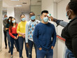 © Jose Carlos Cerdeno/ADDICTIVE STOCK - Group of multiracial colleagues in casual clothes and medical masks passing through procedure of body temperature control for coronavirus prevention before entering workplace