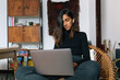 © Joy Zamora/ADDICTIVE STOCK - Low angle of serious Indian female sitting with laptop and reading news online