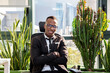 © Jose Carlos Cerdeno/ADDICTIVE STOCK - Positive young ethnic black male employee in casual outfit sitting on chair resting during break in modern workspace looking at camera