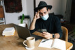 © Joy Zamora/ADDICTIVE STOCK - Pensive ethnic male freelancer wearing medical mask sitting at table in home office and browsing smartphone while working during coronavirus pandemic