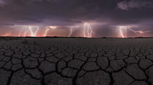 Dark Thunderstorm Sky With Bright Lightnings Striking Above Drought Cracked Lifeless Ground