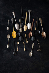 From above of set of various old fashioned spoons placed on black background in studio