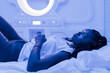 © Julio Rodriguez/ADDICTIVE STOCK - Young black woman resting on bed in contemporary capsule hotel with futuristic interior design and blue illumination looking up