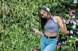 © Julio Rodriguez/ADDICTIVE STOCK - Positive young female in casual outfit having fun and listening to music with headphones and mobile phone while resting in summer park
