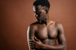 © Luis Manuel Munoz/ADDICTIVE STOCK - Confident African American young male with muscular naked torso standing in trendy jeans with hand on waist on brown background in studio and looking at camera
