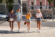 © Manuel Ruiz/ADDICTIVE STOCK - Full body cheerful multiethnic millennial girlfriends in casual outfits and protective masks for coronavirus prevention strolling on urban street in summer day
