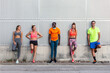 © Manuel Ruiz/ADDICTIVE STOCK - Group of cheerful multiethnic fit runners in sportswear leaning on wall of building while standing on street on sunny day