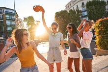 Happy Carefree Teen Female Friends In Trendy Clothes And Sunglasses Having Fun And Dancing Together On Urban Street While Enjoying Summer Day In City
