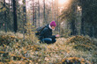 © Miquel Such/ADDICTIVE STOCK - Side view of female explorer sitting in woods in cold season and looking at plants