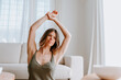 © Mauricio Garay/ADDICTIVE STOCK - Tranquil female stretching arms while sitting on floor at home and enjoying calm morning while looking away